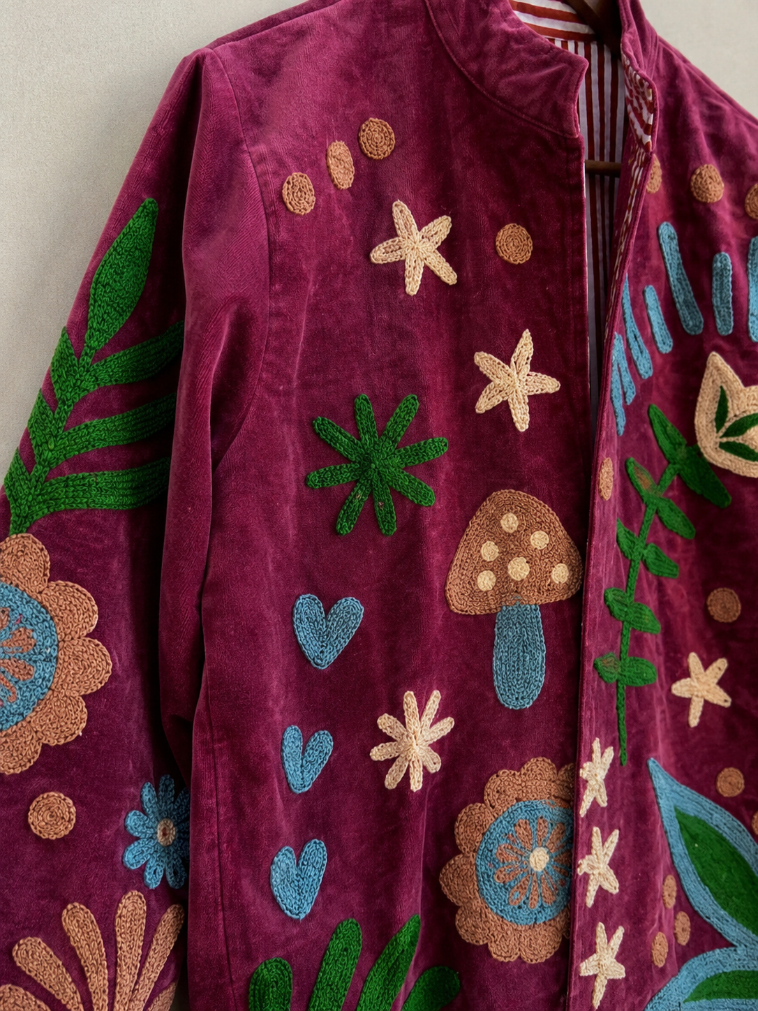 Artisan hand-embroidering gold zardozi botanical motif onto teal velvet
